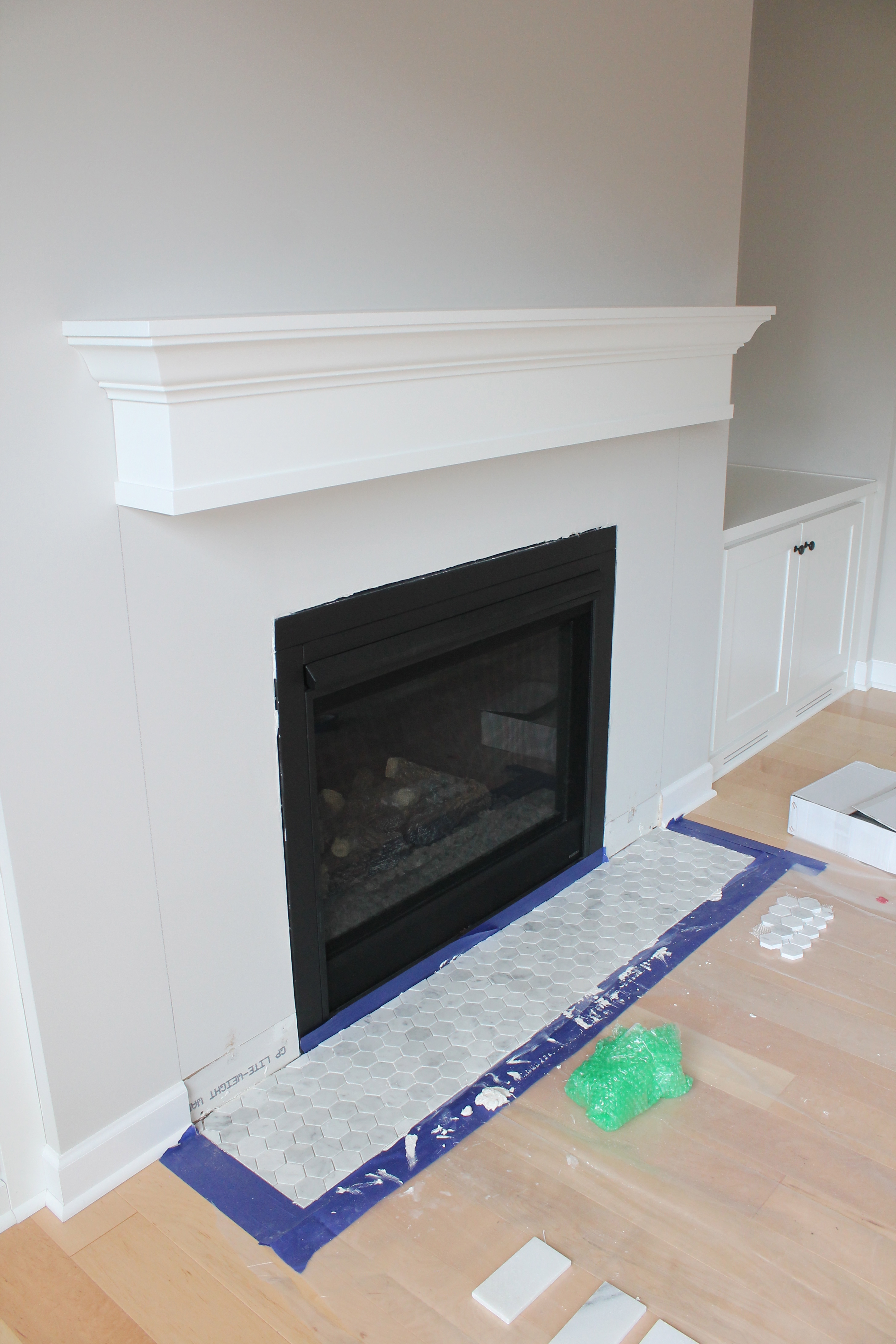 Marble tiles are a common way to add beauty to fireplaces. White is always a marketable and classic color. It is a bright color that reflects light and cleanliness. And marble is an ideal material for low traffic areas like fireplace surrounds. So this tile was a perfect choice!