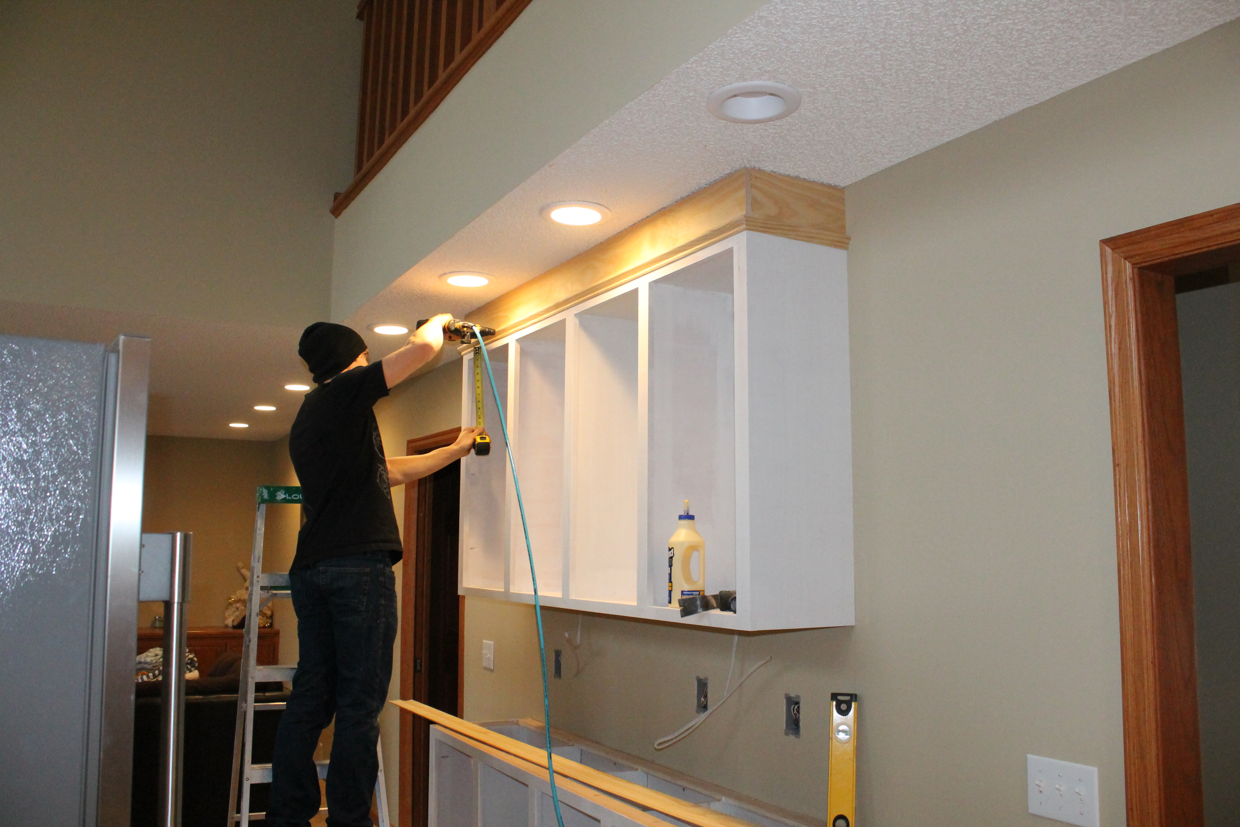 Jamie Molitor putting up custom crown molding for a kitchen remodel with construction2style