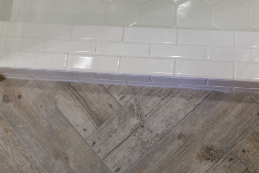 wood tile floor by white tile shower | 5 Plumbing Considerations When Renovating Your Bathroom | construction2style