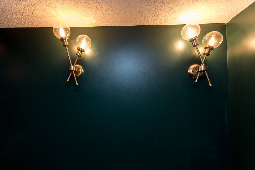 Forest green bathroom accented with gold sconces | construction2style