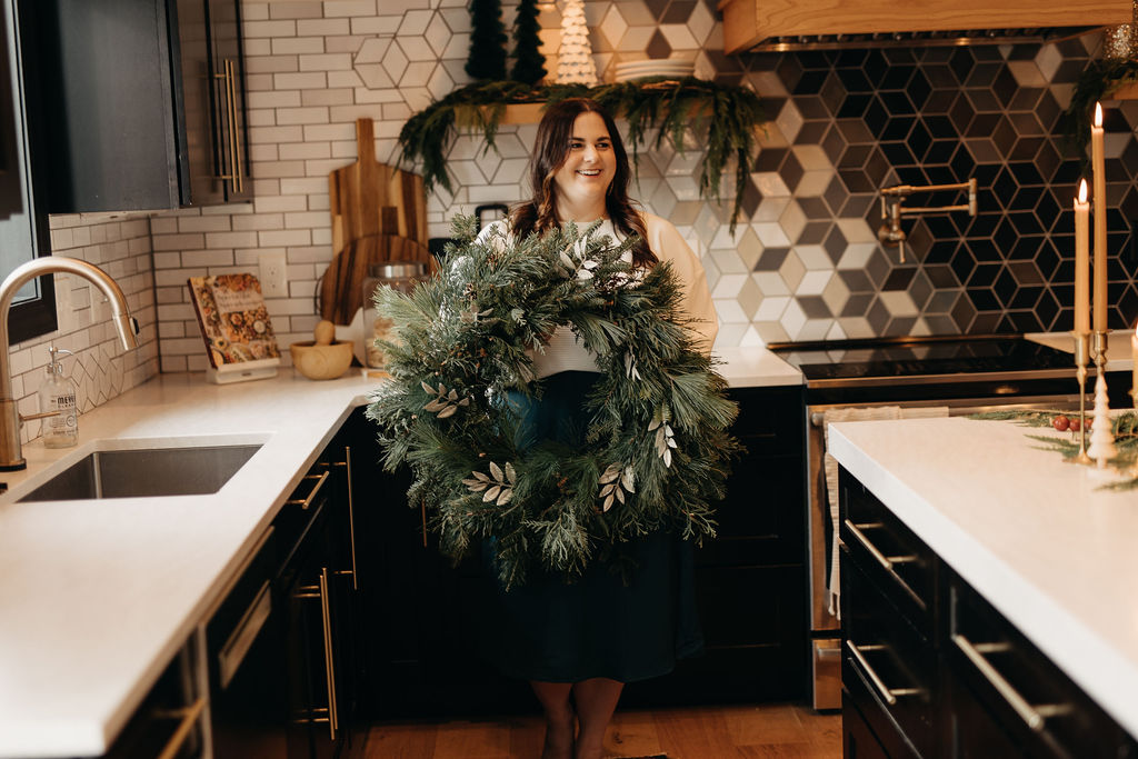 a woman holding a wreath in a kitchen