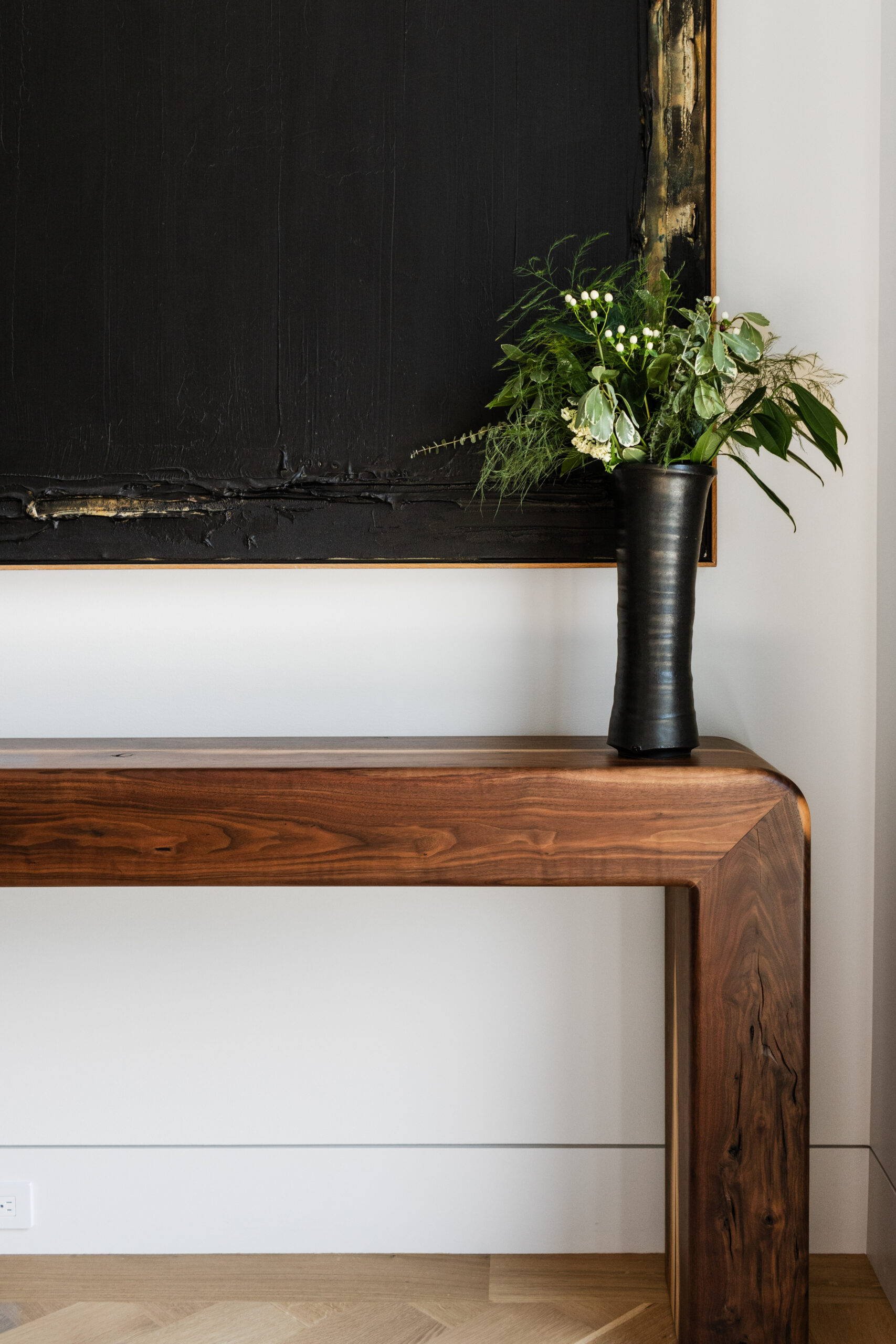 arrowhead artisan home tour | a photo of a modern console table in the entryway with an abstract art above it and a vase with greenery