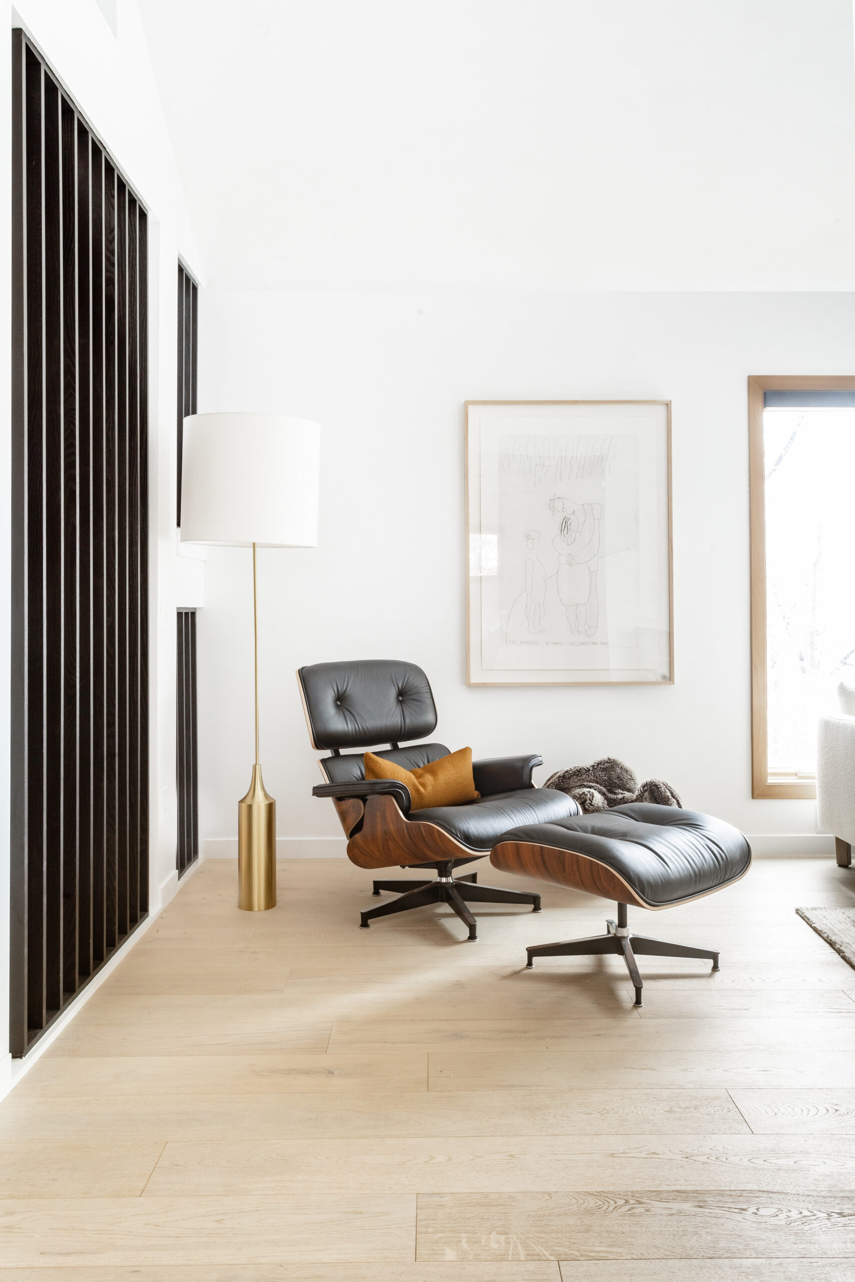 Scandinavian minimalism - living room with a lounge chair, ottoman, floor lamp and an art piece 