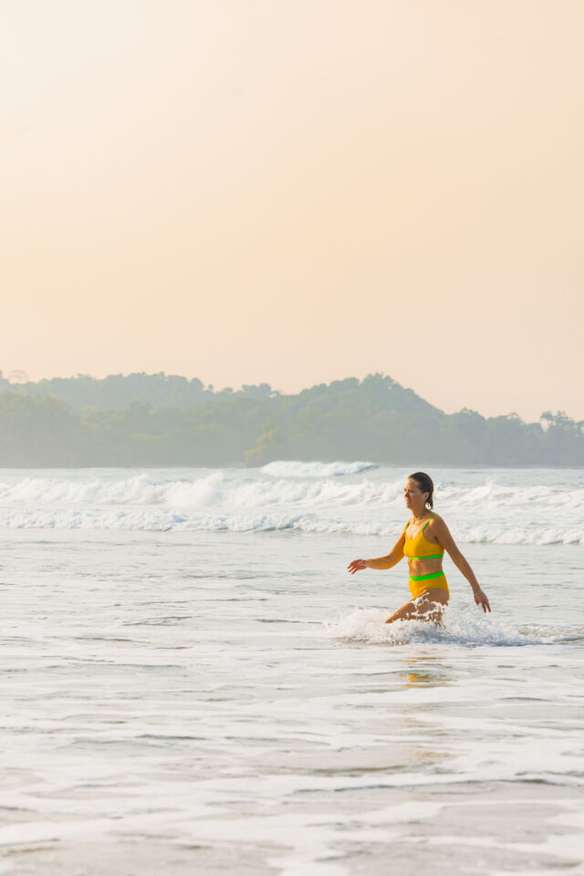 Morgan Molitor in Costa Rica coming out of the water after her swim in a bight yellow two-piece swimsuit