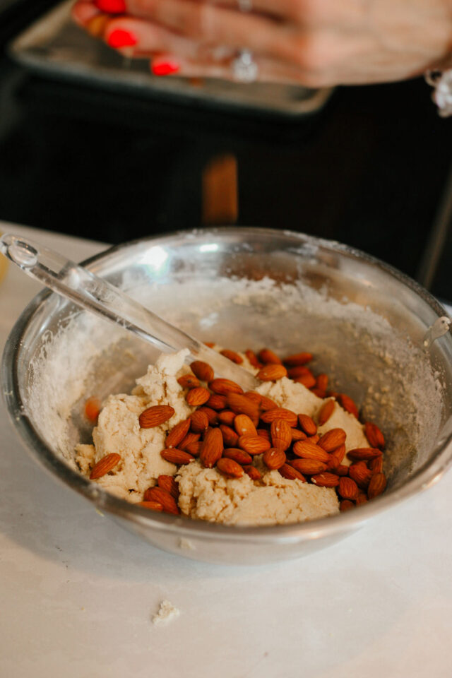 adding roasted almonds to the almond biscotti batter carefully 