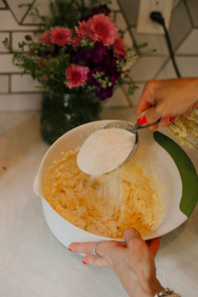 adding flour to butter, sugar and eggs mixture to make cinnamon coffee cake 