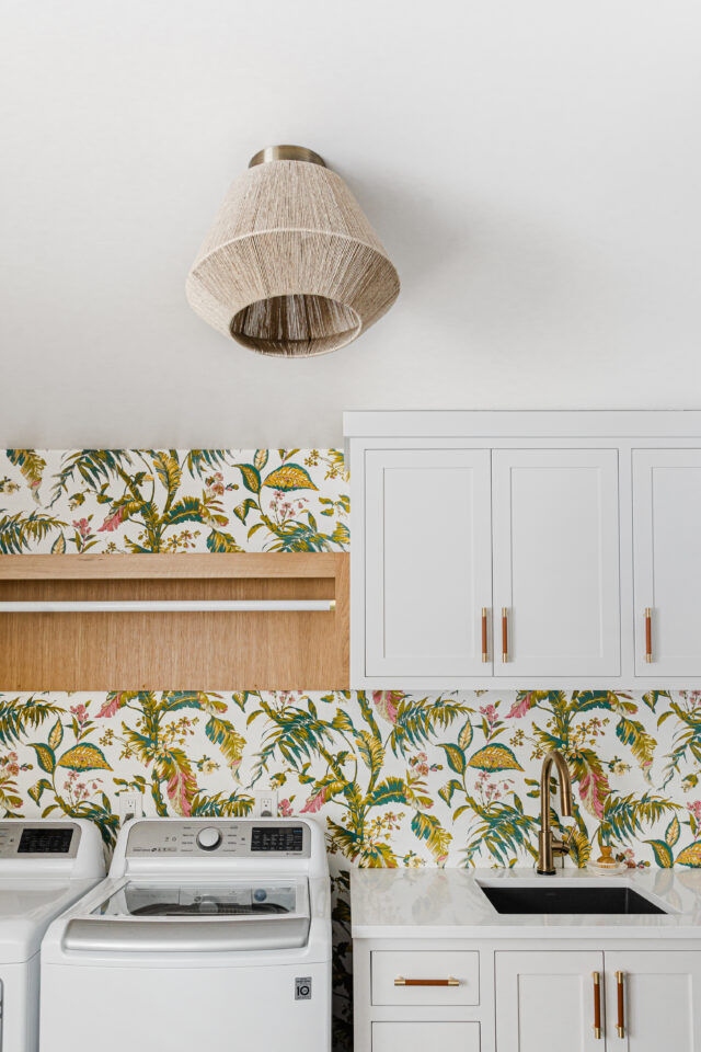 mudroom and laundry room with bright and bold wallpaper and white cabinetry