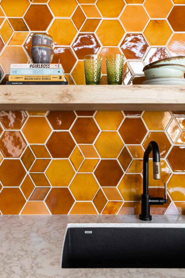 mustard tile is the future of interior design together with floating shelves and bright pottery 