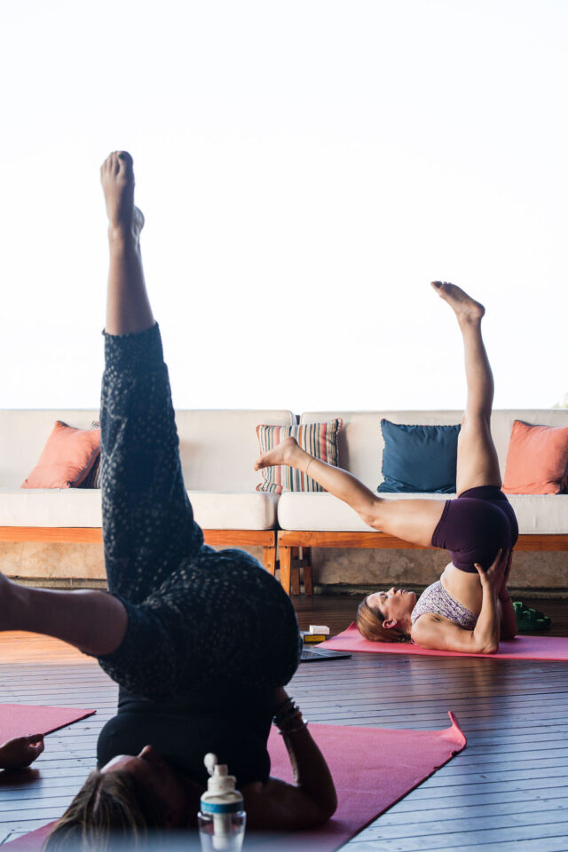 two female contractors are performing a Supported Shoulder Stand during buildher retreat 2025