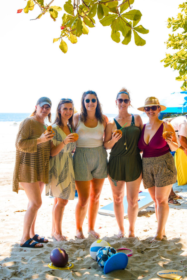 a photo of five female builders holding coconut drinks on the beach while attending buildher retreat in costa rica in 2025 