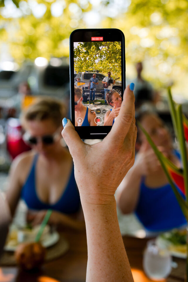 a photo of a female builder holding her phone and recording local singers in Costa Rica, while attending contractor conference for women called buildher retreat 2025