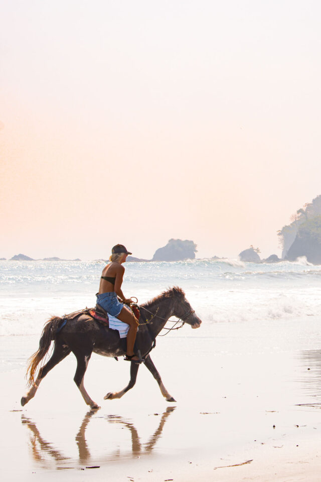 a photo of a female contractor riding a horse on the beach in Costa Rica, while attending contractor conference for women called buildher retreat 2025