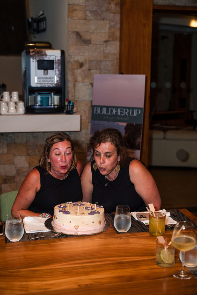 Jill Jinsen of construction2style and her female contractor colleague blowing candles of the birthday cake together while at buildher retreat 2025