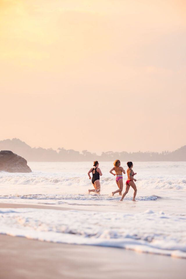 a photo of Morgan Molitor of construction2style and her two colleagues, running into the ocean at sunrise at contractor conference for women called buildher retreat 2025