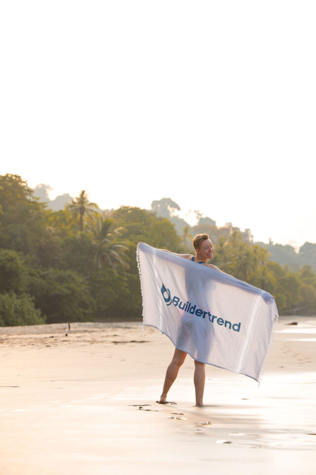 a female contractor holding Buildertrend towel at the beach in costa rica at buildher retreat 2025