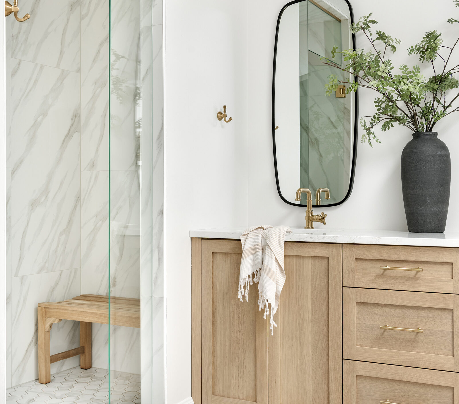 a photo of a primary bathroom designed and built by construction2style, it features a beautiful double vanity in rift sawn white oak, gold hardware, Rochester Accent Mirror placed vertically