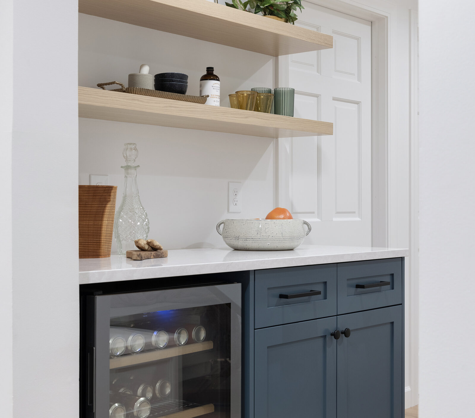 a photo of a drybar in the lower lower, designed and styled by construction2style | small fridge, base cabinetry, drawers with rift white oak shelves by Sean's Cabinetry